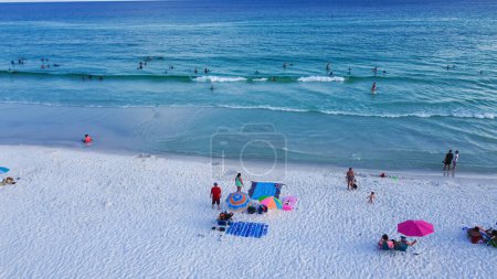Téléchargez les photos : Miramar Beach avec rivage sablonneux blanc, eau turquoise, vagues bleues et foule de personnes diverses nageant, relaxant, tentes colorées, verrière, chaise longue, Destin, Floride. Destination de voyage - en image libre de droit