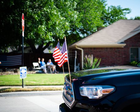 Téléchargez les photos : Couple âgé flou agitant les mains avec une camionnette moderne conduisant sur une petite ville de rue résidentielle Quatrième défilé de juillet, Dallas, Texas, États-Unis maisons résidentielles en arrière-plan. Jour de l'indépendance patriote - en image libre de droit