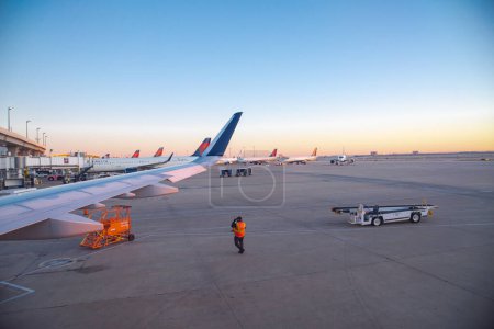 Foto de NOV 13, 2022-DALLAS, TX, US: Miembros de la tripulación de operaciones de aeródromo por seguridad, eficiencia de la aviación a aeronaves Delta Air Lines en el aeropuerto Dallas-Fort Worth DFW, vuelos domésticos. Transporte. - Imagen libre de derechos