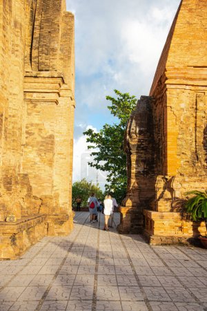 Téléchargez les photos : Touristes prenant des photos à l'espace étroit entre la tour nord ou Thap Chinh et la tour centrale ou Thap Nam de Ponagar Cham Tours, toit pyramidal en terrasses, construit en partie en briques recyclées. Viêt Nam - en image libre de droit