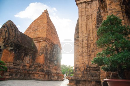 Photo for Unidentified tourists walking along narrow space between North Tower or Thap Chinh and Central Tower or Thap Nam of Ponagar Cham Towers, terraced pyramidal roof, built partly recycled bricks. Vietnam - Royalty Free Image