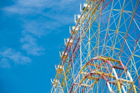 Close-up upward view the support frame of modern colorful Ferris Wheel with axle, rim, spoke cable, sightseeing cabin, steel stands weight of all components, rotation of the force and torque. Vietnam