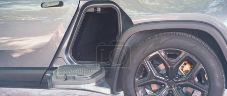 Photo for Panorama horizontal storage space gear tunnel be accessed from either side of modern electric vehicle pickup truck outdoor, special accessories compartment underneath second row passenger seats. USA - Royalty Free Image