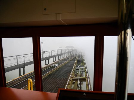 Foggy misty winter weather cover tram railway, lifted aerial funicular electric railway from Sapa to Muong Hoa Station cable car Fansipan, Vietnam, view from driver cabin, electric light rail. Travel