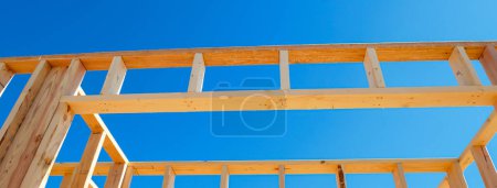 Panorama wooden exterior interior walls framing house, rough openings for doors and windows on newly set foundation of medium size single family residential home in Dallas, Texas, clear blue sky. USA
