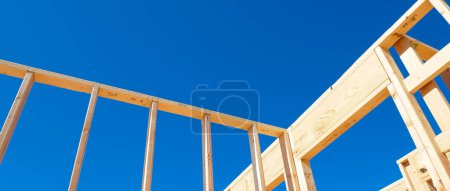 Panorama wooden exterior interior walls framing house, rough openings for doors and windows on newly set foundation of medium size single family residential home in Dallas, Texas, clear blue sky. USA