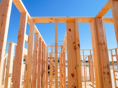 Close-up wooden framing, joints, post, beam connection of medium size single family residential home, Dallas, Texas, interior view traditional timber house new build construction, clear blue sky. USA