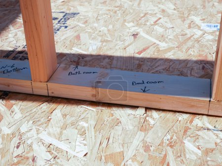 Photo for Post beam stud timber framing with marker on OSB sub flooring sheets cover, attach to joists with wood screws Oriented Strand Board plywood, new house construction, interior wall framing, Texas. USA - Royalty Free Image