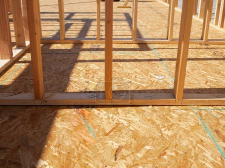 OSB sub flooring sheets cover, attach to the joists with wood screws Oriented Strand Board plywood, timber framing with posts beams studs of new house construction, interior wall framing, Texas. USA