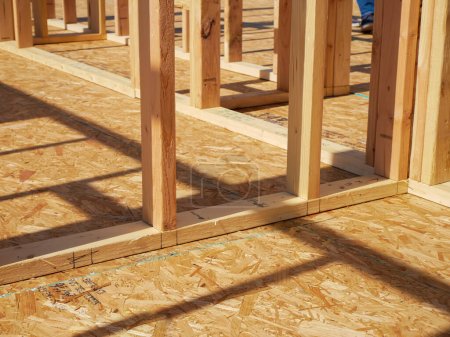 OSB sub flooring sheets cover, attach to the joists with wood screws Oriented Strand Board plywood, timber framing with posts beams studs of new house construction, interior wall framing, Texas. USA