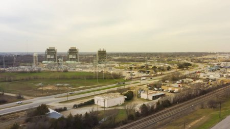 Foto de Zona industrial del sistema ferroviario con autopista y central eléctrica tres unidades de megavatios de instalaciones de generación eléctrica alimentadas con gas natural en Fort Worth, Texas, generan electricidad mediante la quema de gas. Antena - Imagen libre de derechos