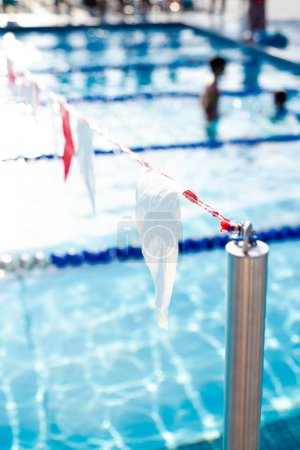 Photo for Stainless steel pole ties string of colorful triangle polyester vinyl backstroke flags and blurred swimming class coach, little student background, Dallas, Texas, pool lane divider rope and float. USA - Royalty Free Image