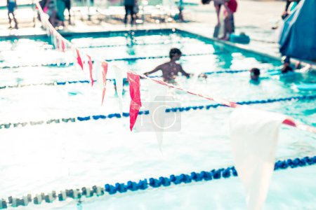 Banderas de espalda y clase de natación borrosa para niños pequeños con audiencia de entrenadores y padres en la piscina competitiva pública de verano en Dallas, Texas, cuerda divisoria de carril de piscina y carrozas. Estados Unidos