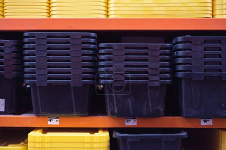 Price tag and full shelves of tough black tote durable recycled polypropylene with yellow reinforced snap-fit lid, lockable lid to secure protect storage items, hardware store in Dallas, Texas. USA