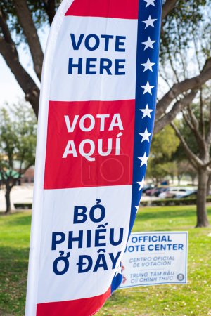 Photo for Political vote flag in multiple language English, Spanish, Vietnamese shows Vote Here text, polyester double-sided election decorations polling locations rotating spike base, Dallas, TX. USA - Royalty Free Image