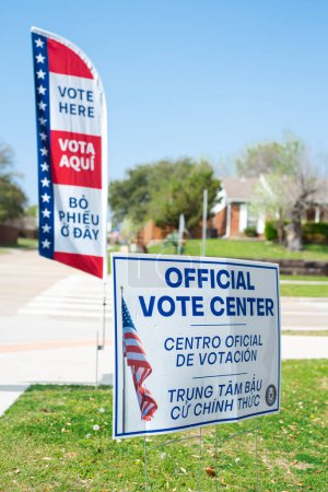 Photo for Residential street intersection with yard sign, vote banner flag show Official Vote Center in English, Spanish, Vietnamese welcome non-English-proficient groups to voting location Dallas, Texas. USA - Royalty Free Image