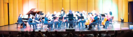 Photo for Panorama blurred classic symphony orchestra with diverse performers, conductor, selection of string, wind, bass, percussion instrument, violin, cello, trumpet, piano indoor spotlight stage in TX. USA - Royalty Free Image