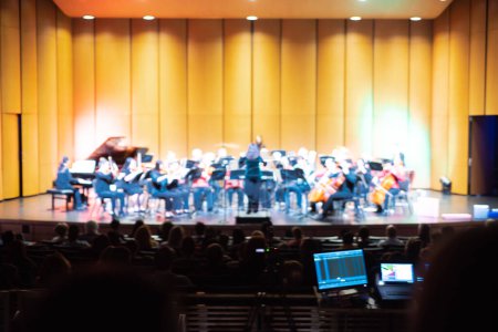 Photo for Toned photo blurred classic symphony orchestra with diverse performers, conductor, selection of string, wind, bass, percussion instrument, violin, cello, trumpet, piano indoor spotlight stage, TX. USA - Royalty Free Image
