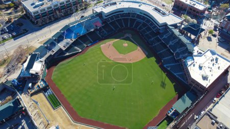Large ballpark baseball field with team playing tournament at downtown Oklahoma City, aerial view entertainment district with high rise loft apartment condos, office building, busy parking street. USA