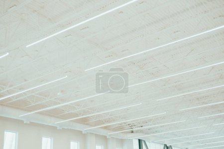 Tall warehouse style building with large windows for natural light and modern roof beam spot LED lights, suspended ceiling metal roof structure, steel warehouse industry factory building, Texas. USA