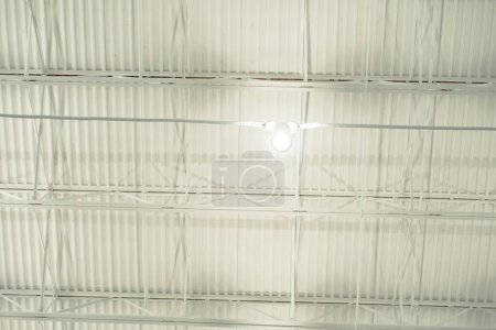 Spot light hanging at modern suspended ceiling metal roof structure, warehouse industry factory building lighting solution, stretch ceiling perimeter track and membrane clicks into, Frisco, TX. USA