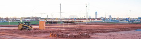 Panorama view construction site groundworks and downtown Oklahoma City background, Monarch Highway or Interstate-35, Prospect Avenue, Grand boulevard overpass, portable toilet, excavator machine. USA