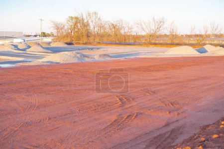 Crushed gravel piles up heap at construction site near warehouse district North of Oklahoma City, truck tire tread machinery prepares the ground foundations, earthwork, industrial background. USA