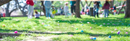 Panorama abundant of colorful Easter eggs on green grass field with blurry diverse people kids parents waiting behind vinyl tape barricade for eggs hunting tradition at local Church, Dallas, TX. USA
