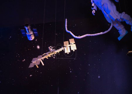 Téléchargez les photos : Modèle d'astronaute avec cordon ombilical de sécurité attache sortie spatiale promenade autour de la Station spatiale internationale, structure de treillis intégrée, orbite Terre et galaxie suspendue au plafond du musée au Texas. États-Unis - en image libre de droit