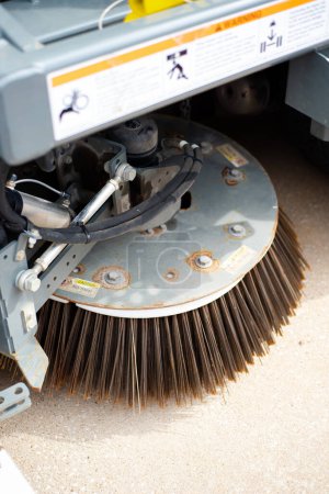 Photo for Close-up side gutter broom on modern single-engine mechanical sweeper truck with steel plate disc, dual free-floating brooms, hydraulic trailing arm adjust to variable road surfaces, curbs angle. USA - Royalty Free Image