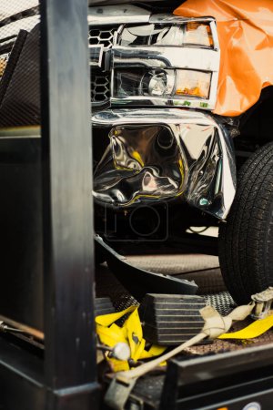 Toned foto aplastado guardabarros delantero en la camioneta por accidente de coche en la bandeja de inclinación de cama plana de remolque con amarilla correa de trinquete atar, colisión, concepto de reclamación de seguro, Texas. Estados Unidos