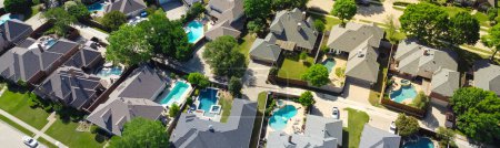 Panorama aerial view lush greenery suburban residential neighborhood subdivision, row upscale two-story houses, swimming pool, shingle roofing, large fenced backyard, well-trimmed HOA landscape. USA