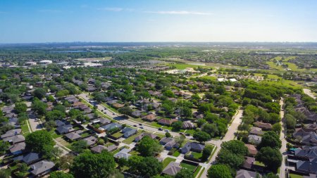 Suburbs subdivision with downtown Dallas background, row of residential houses with school district, natural lake, lush greenery landscape, upscale homes swimming pool, grassy front yard, aerial. USA