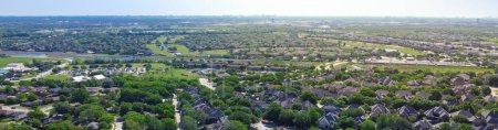 Panorama suburbs subdivision with downtown Dallas background, row of residential houses with school district, lake, lush greenery landscape, upscale homes swimming pool, grassy front yard, aerial. USA