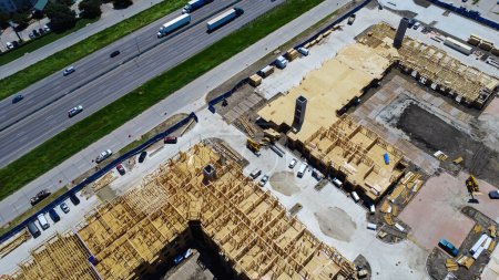 Photo for Interstate 35 highway and large apartment complex under construction, Dallas, Texas, Slab foundation, precast concrete elevator shafts, wooden framework of multi-story rental community, aerial. USA - Royalty Free Image