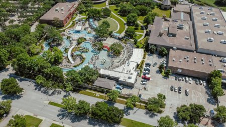 Aerial view outdoor pool complex with lazy river, waterslides, shaded lounge chairs, picnic areas of business hotel near downtown Dallas, Texas, Stemmons Corridor neighborhood in North Texas. USA