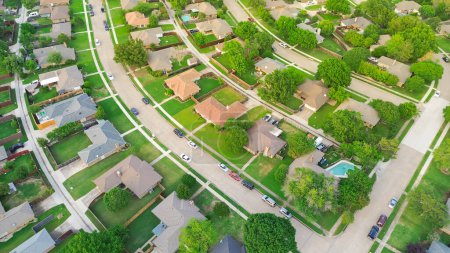 Residential streets with parked cars along row of suburban houses well-trimmed front yard landscape in subdivision suburbs Dallas, Texas, aerial detached single family homes large backyard fence. USA