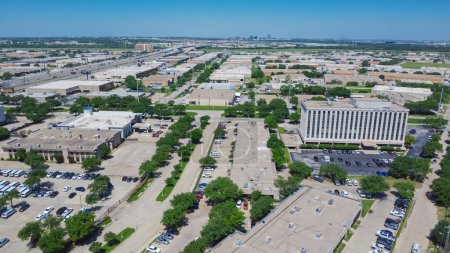 Northwest Dallas business park with ample parking spaces, group of office buildings, hotels, restaurants in Love Field neighborhood with mid-town buildings skylines background, aerial view. USA