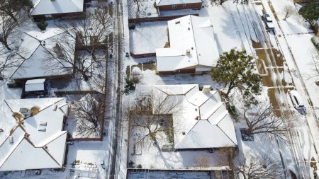 Casas suburbanas y calles residenciales cubiertas de nieve pesada en los suburbios Dallas, Dallas-Fort Worth área metropolitana impactos por el clima severo, el cambio climático, el sol y la nieve derretida, aérea. Estados Unidos