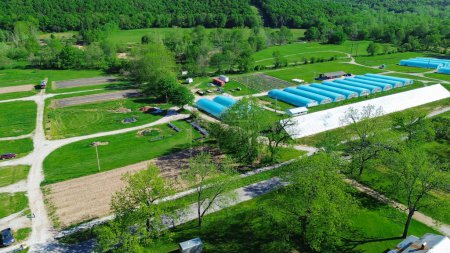 Lush greenery Ozarks area with repetitive aerial view row of high tunnel greenhouse or polyhouse, hoophouse, extra-long polythene growing hothouse at commercial farm in rural Mansfield, Missouri. USA