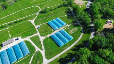 High tunnel greenhouse on large grassy vacant land near entrance of commercial farm in Ozarks aera, Mansfield, Missouri, aerial view polyhouse, hoophouse extra-long polythene growing hothouse. USA