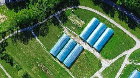 Aerial view high tunnel greenhouse on large grassy vacant land of large commercial farm in rural Ozarks aera, Mansfield, Missouri, row polyhouse, hoophouse extra-long polythene growing hothouse. USA