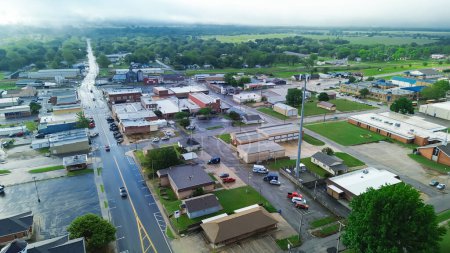 Gentry avenue along historic downtown of Checotah in McIntosh County, Oklahoma under foggy misty morning, aerial view small town with red brick buildings, antique malls, quiet street early summer. USA