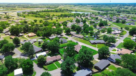 Suburban houses along W McIntosh Ave and SW 5th St in Checotah town, McIntosh County, Oklahoma with intersection of Interstate I-40 and Highway 69 in background, aerial view single family homes. USA