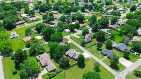 Residential neighborhood along Jefferson and Gentry Ave in Checotah, McIntosh County, Oklahoma, row of single-family houses with large backyard, grassy lawn, lush green tall mature trees, aerial. USA