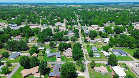 Aerial view suburbs of Checotah, McIntosh County, Oklahoma toward north of interstate I-40, east of Highway 69, suburban single-family houses on large lot size lush trees along 4th street, sunny. USA