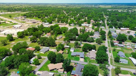 Aerial view suburbs of Checotah, McIntosh County, Oklahoma towards north of interstate I-40, east of Highway 69, suburban single-family houses on large lot size lush trees along 4th street, sunny. Estados Unidos