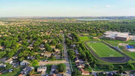 Lakeside urban sprawl lush greenery neighborhood, school district sport complex football field, tennis court, running track, playground in residential area Dallas Fort Worth Metro complex, aerial. USA
