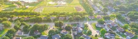 Panorama aerial neighborhood with cul-de-sac dead-end key hole shape street in school district of middle, elementary school football field, tennis court, playground, Dallas Fort Worth suburbs. USA