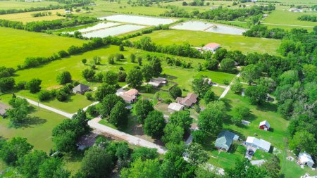 Group of farmhouses on large lot size acre surrounding by lush green trees, storage sheds and large farmland, pond system in Fairland, Oklahoma, rural American industry aerial view grassy field. USA